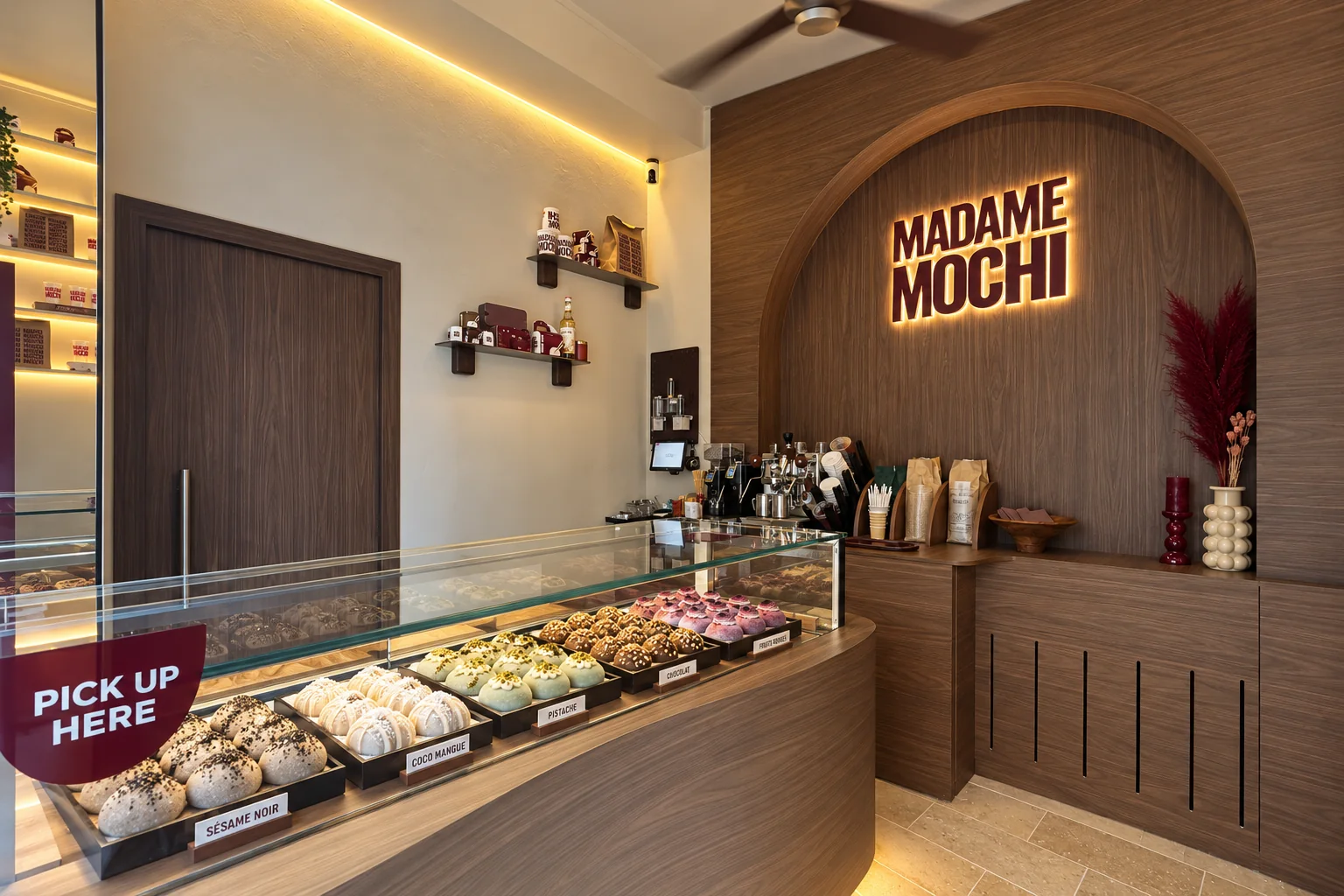 Le comptoir en noyer qui s'arrondit jusqu'à l'arche et au logo lumineux, les plateaux de mochis sous la vitre